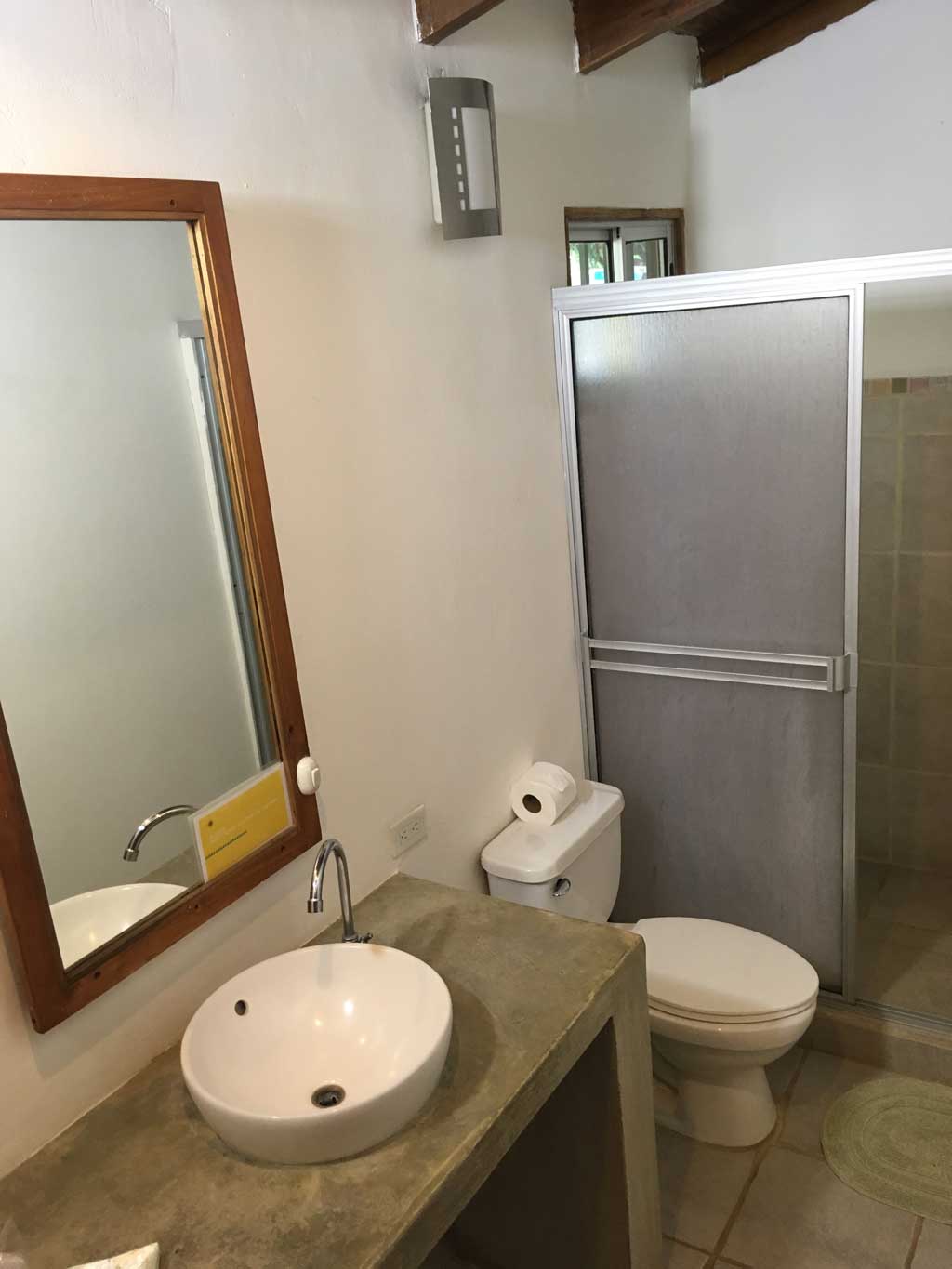 Modern appliances and rustic concrete design in en suite bathroom of triple room at Indra Inn