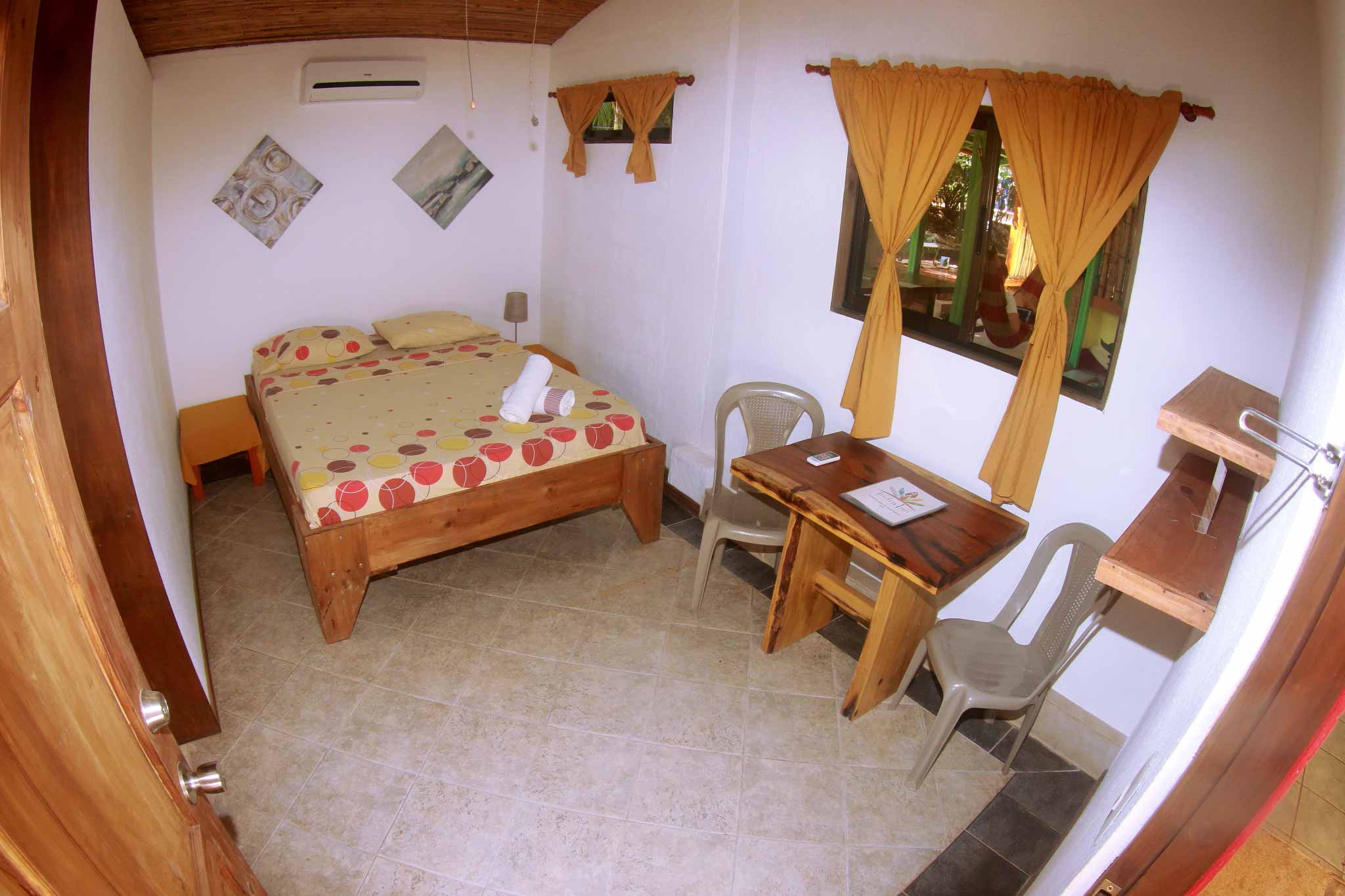 Fisheye view of double room at Indra Inn with warm decoration and solid wood furniture