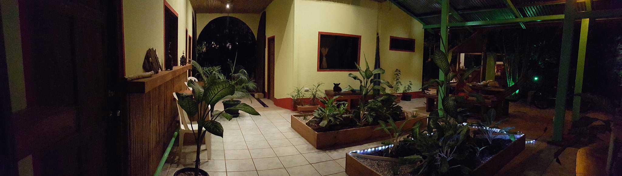 Panorama of indoor gardens and lounge area at night in Indra Inn