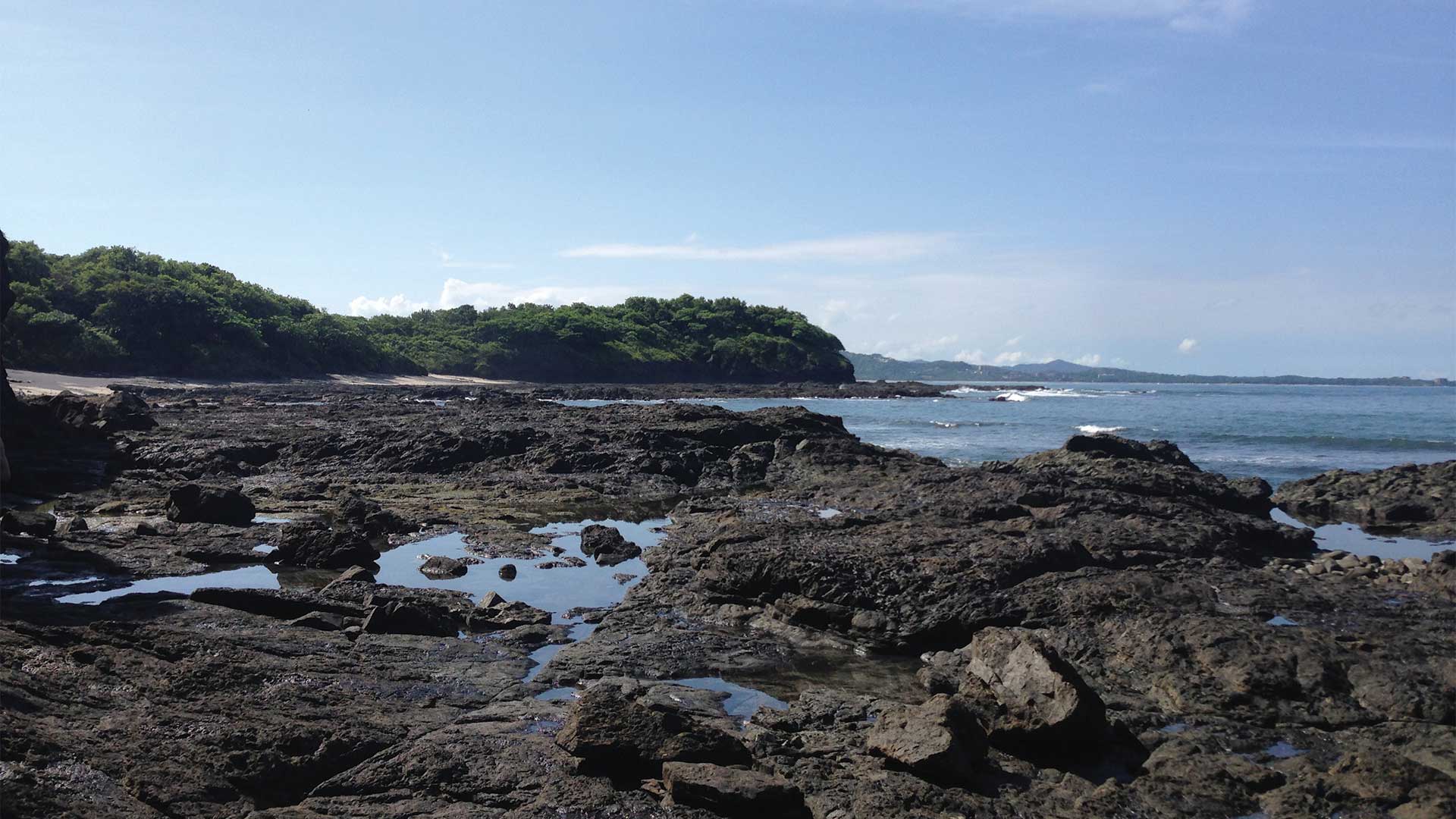 Black rocky beach with tide pools at Playa Carbon in Guanacaste, Costa Rica