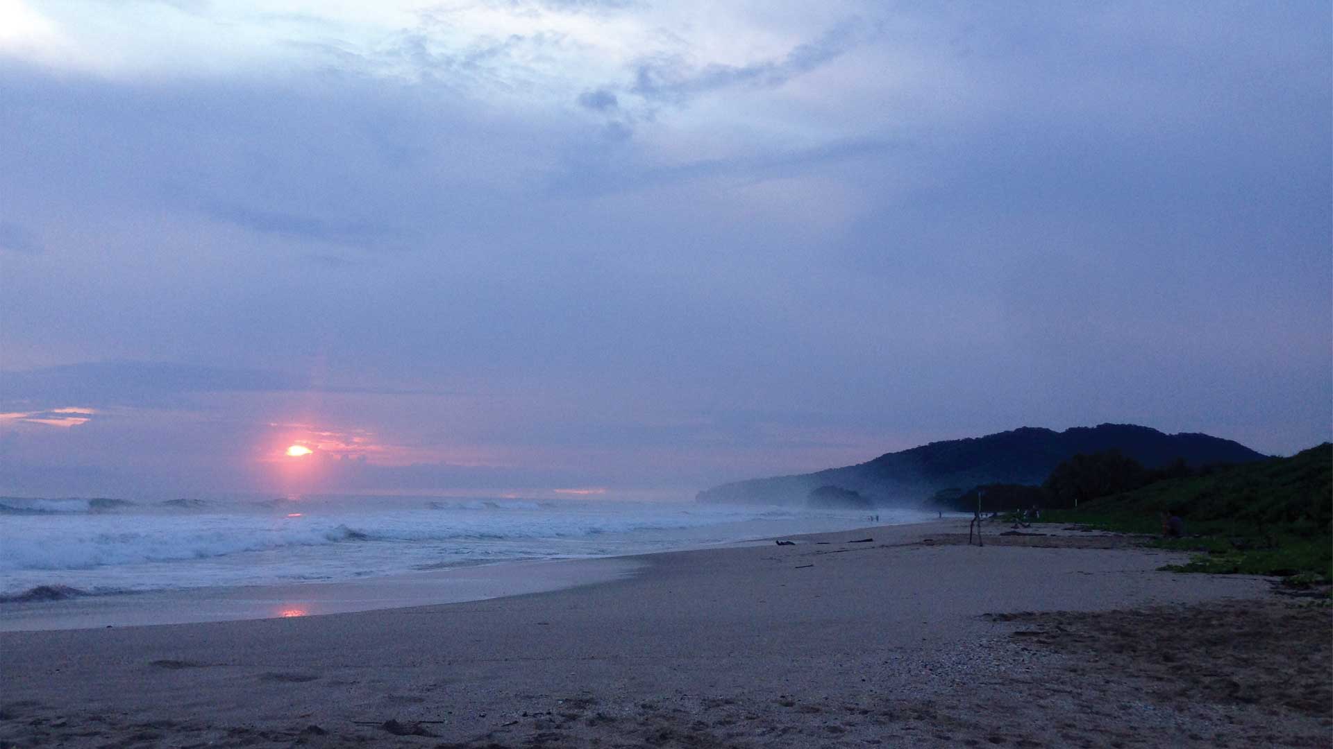 Dark misty sunset over Playa Grande empty wide sandy beach in Guanacaste, Costa Rica